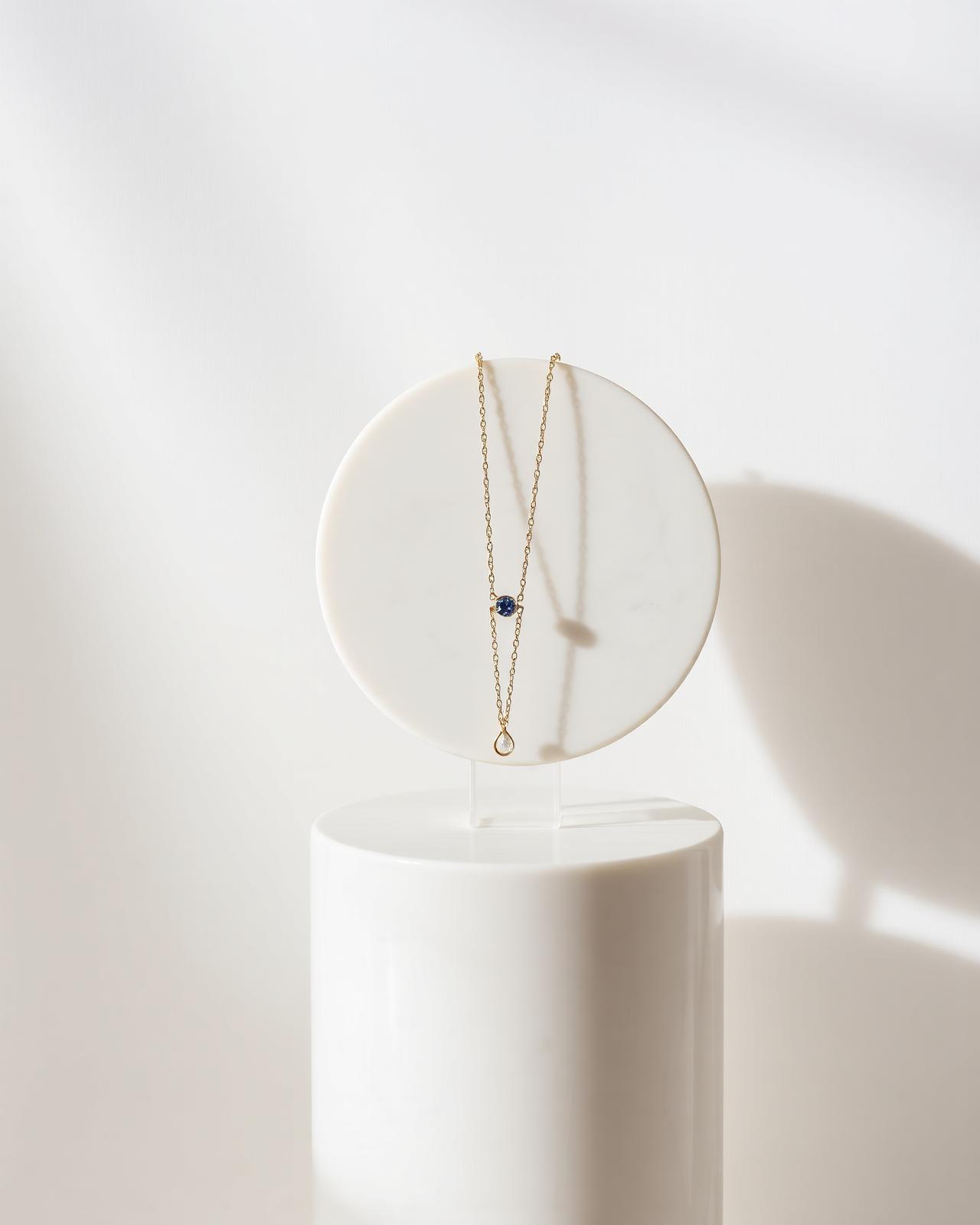 Umay Luxe — fine gold necklace on a white marble pedestal